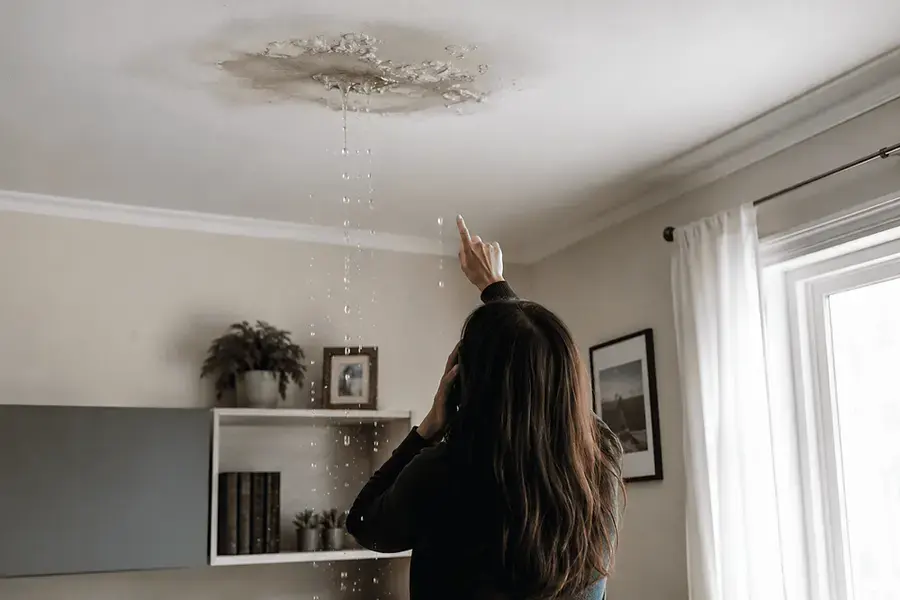 Resident pointing at water dripping from a stained ceiling in a living room
