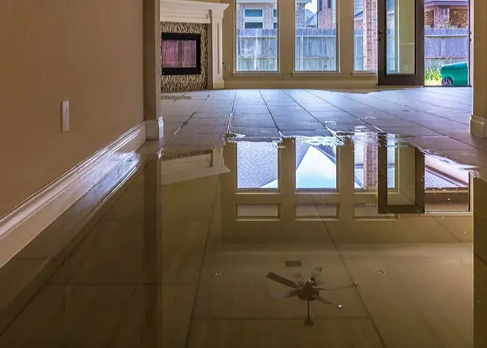 Standing floodwater covering the tile floor of a living room and reflecting the windows
