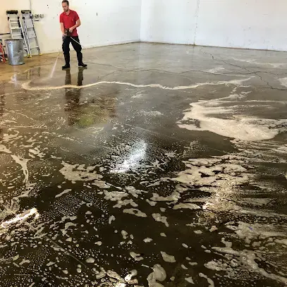 Technician working floodwater off a concrete floor with a wand